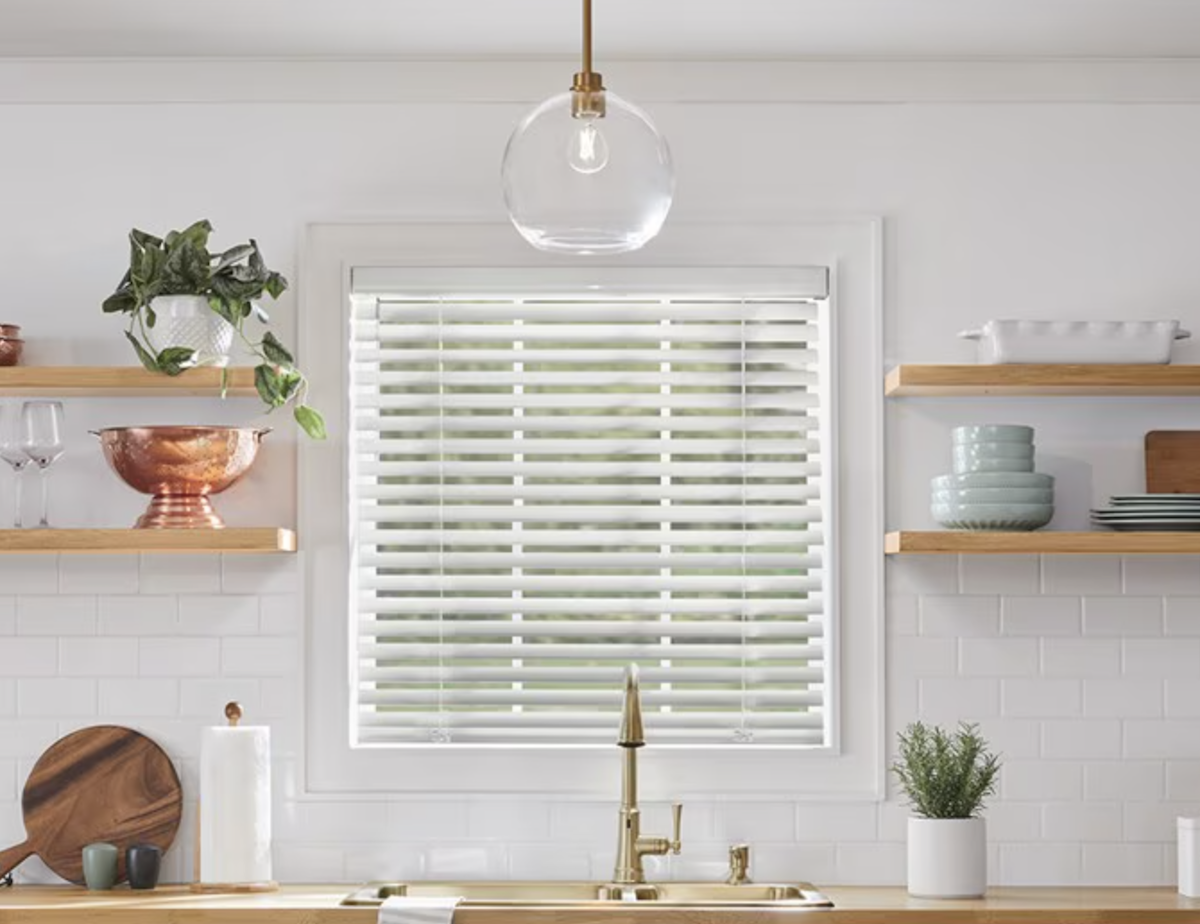 Aluminum blinds hanging on small window above a kitchen sink window. 