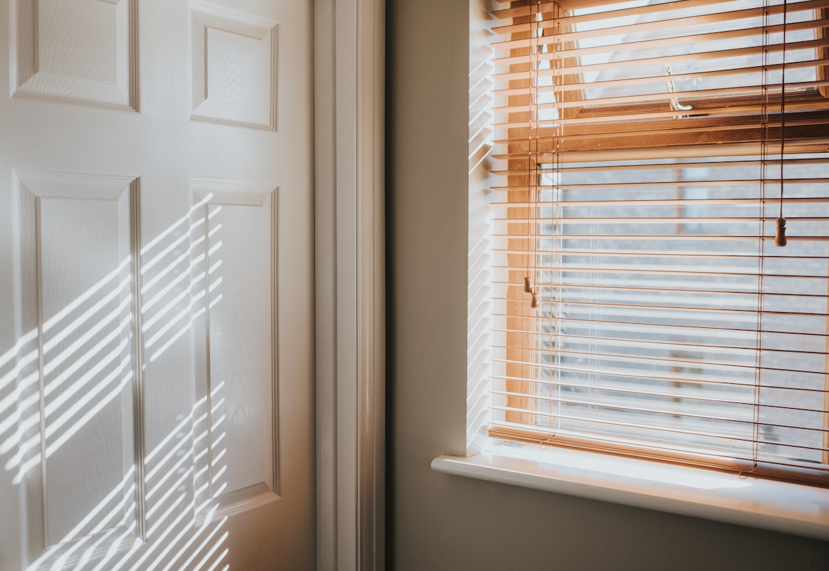 A bright room with light filtering wooden blinds.