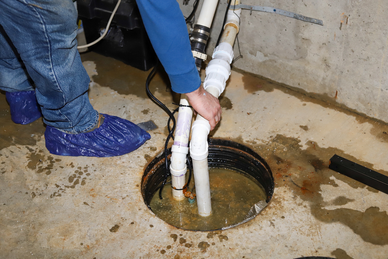 A man repairing a sump pump in a flooded basement
