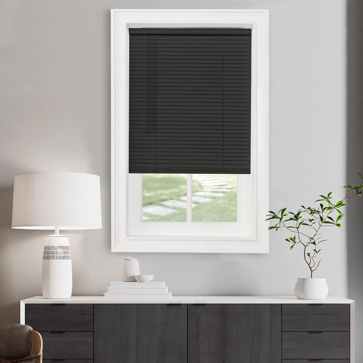 Charcoal grey mini blinds on a small window situated above a hutch. 