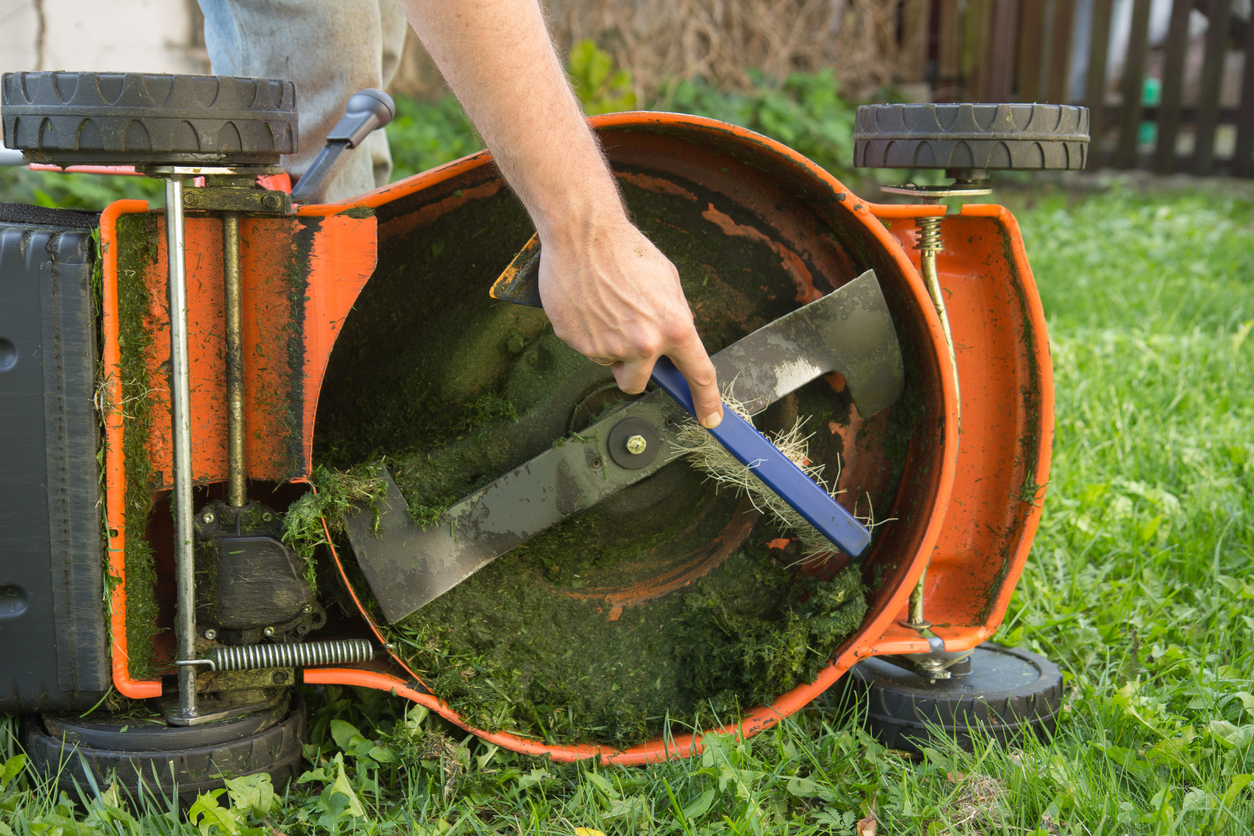mowing mistakes everyone makes man cleaning bottom of lawnmower