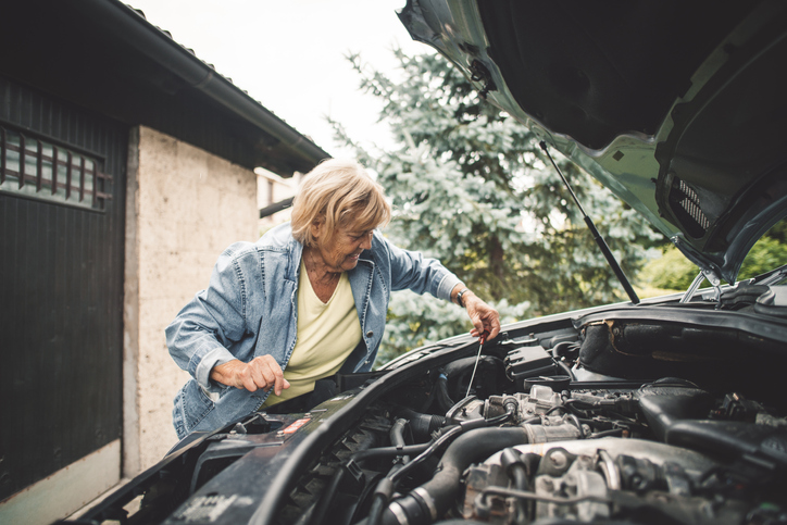 spring-car-maintenance-senior-woman-checks-engine-oil-in-car