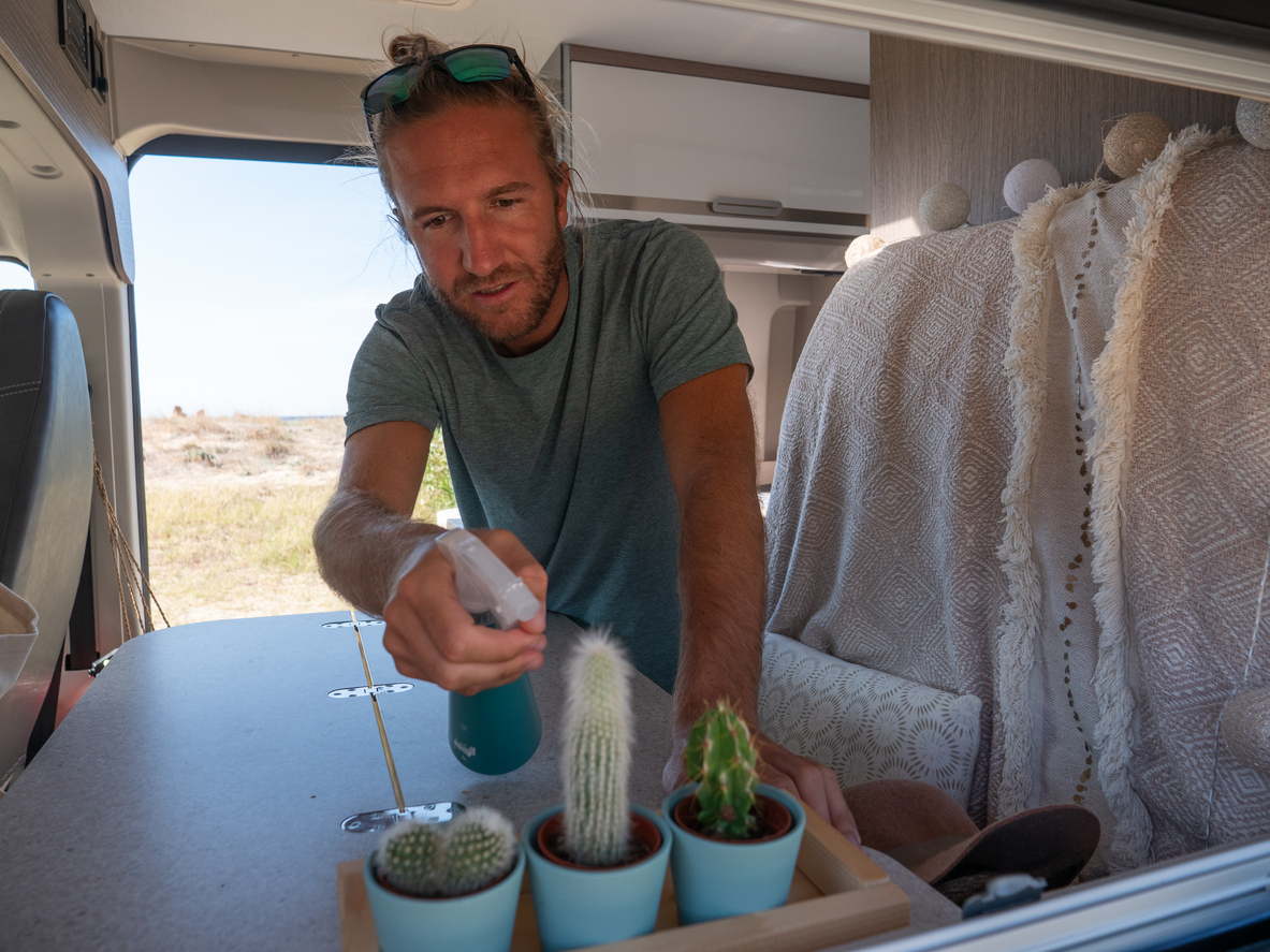 iStock-1330354625 camper decor man watering cactus plants in RV