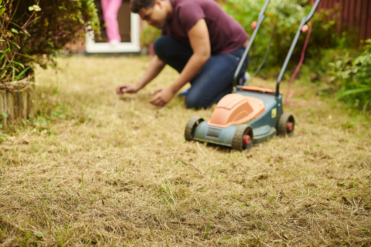 mowing mistakes everyone makes man caring for drought affected lawn with lawnmower not in use