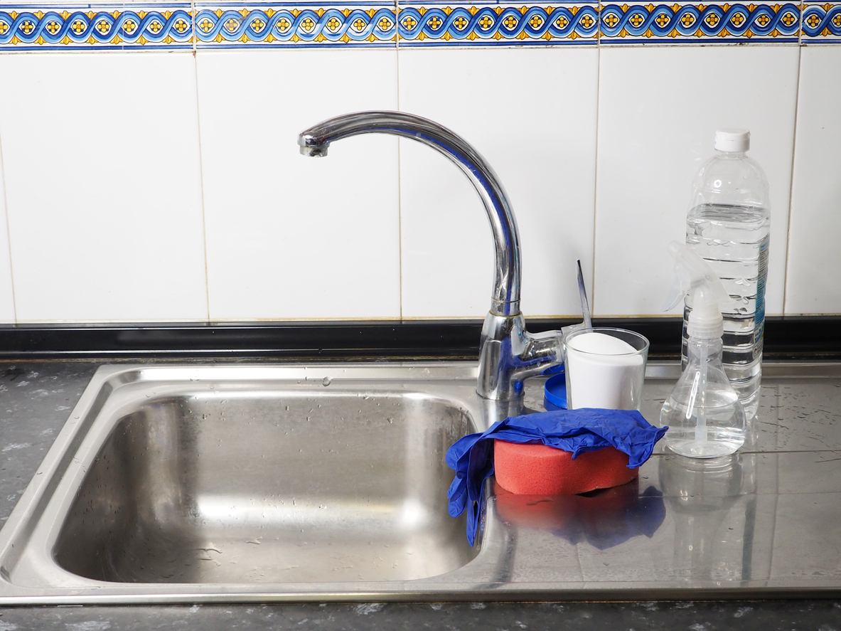 iStock-1440484035 how to unclog a sink drain baking soda, white vinegar, a sponge on the kitchen sink