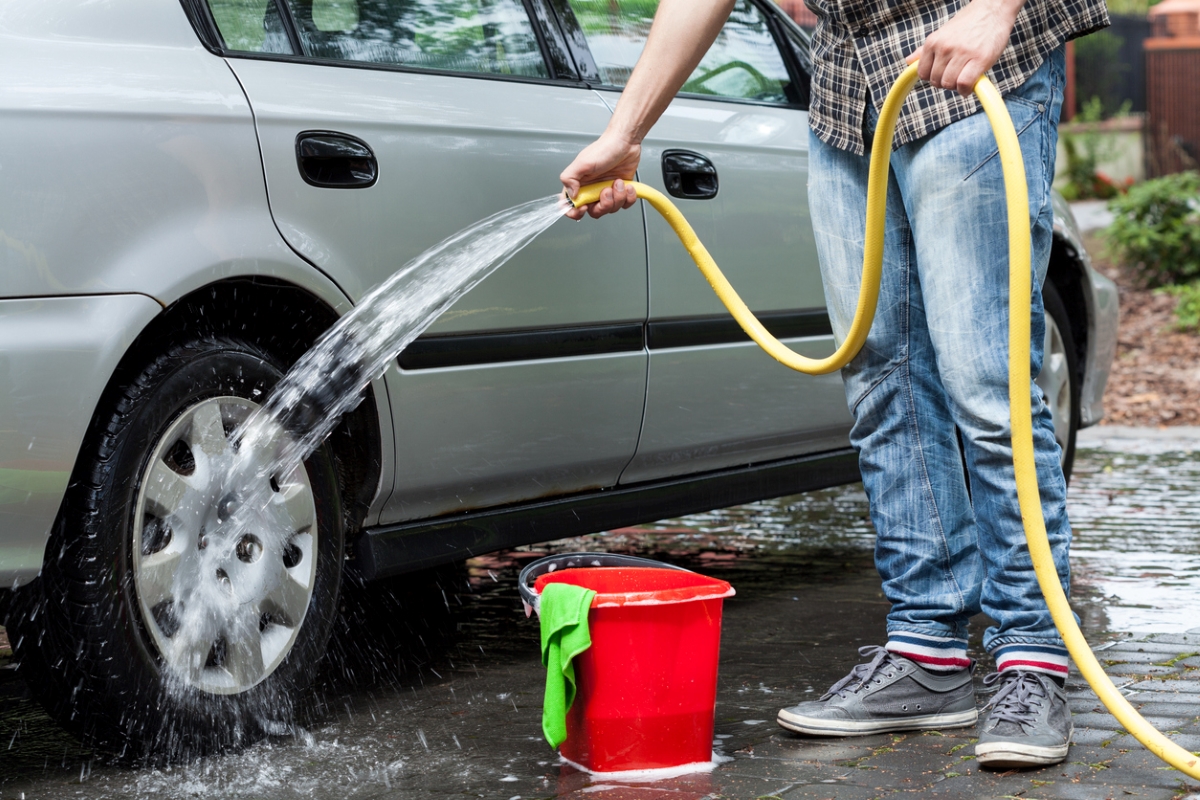 car maintenance tasks - person using hose to clean car