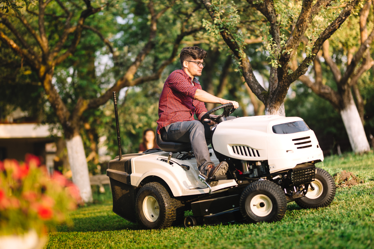 mowing mistakes everyone makes man riding lawn mower in orchard
