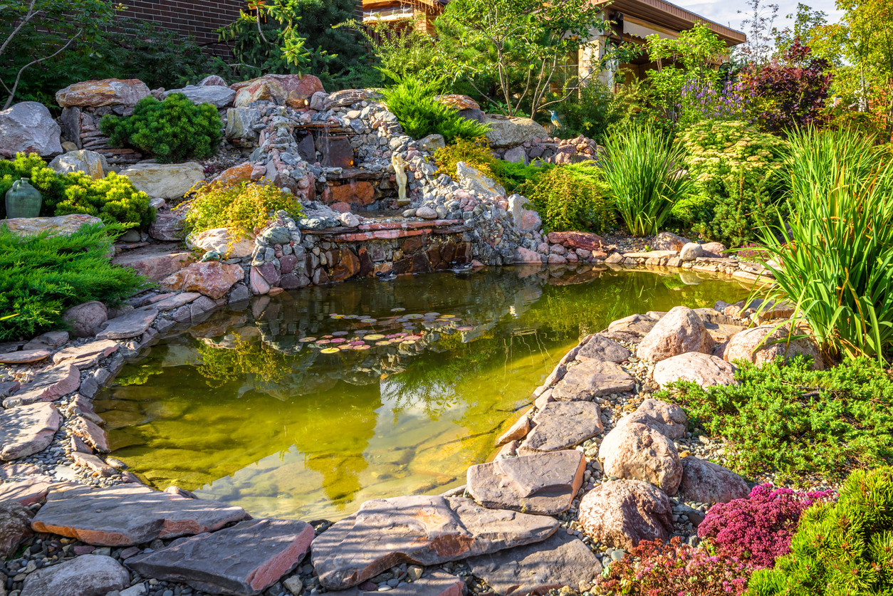 large water feature pond with stones and waterfall in backyard