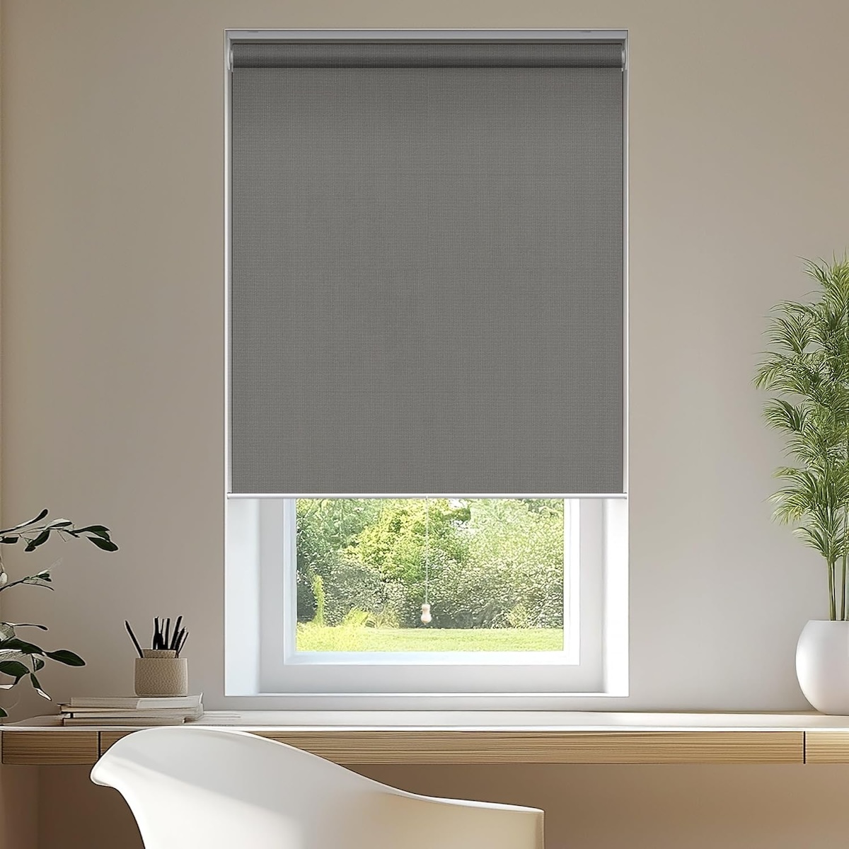 A rectangular window in a white living room with grey roller blinds. 
