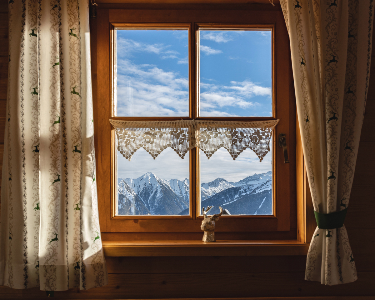 White apron curtains patterned with green deer on a mountain-view window