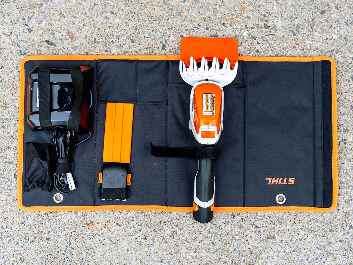 The Stihl cordless garden shears laid out next to included attachments atop the organizer case