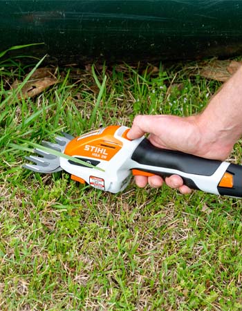 The Stihl cordless garden shears with attached grass trimmer in position to trim grass