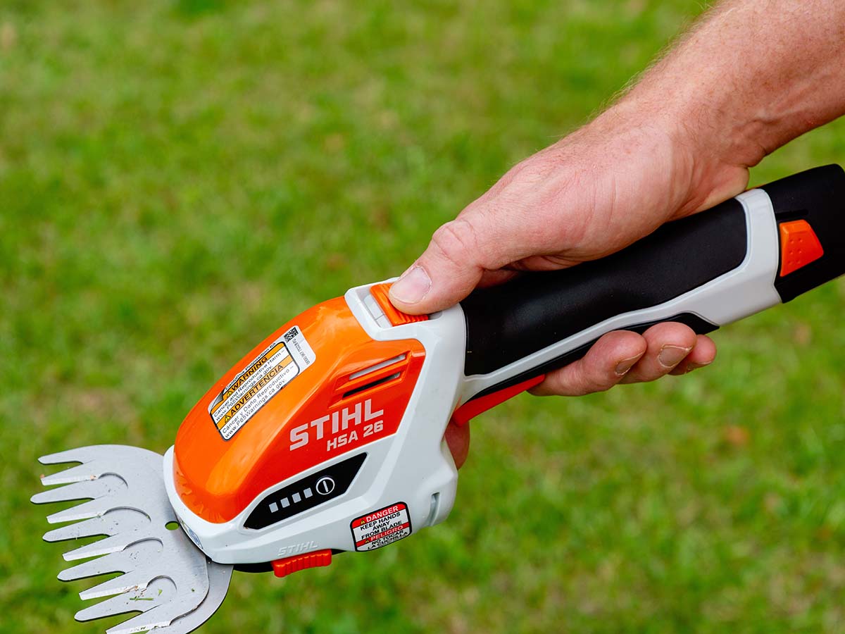 Close-up of a man's thumb on the safety switch of the Stihl cordless garden shears