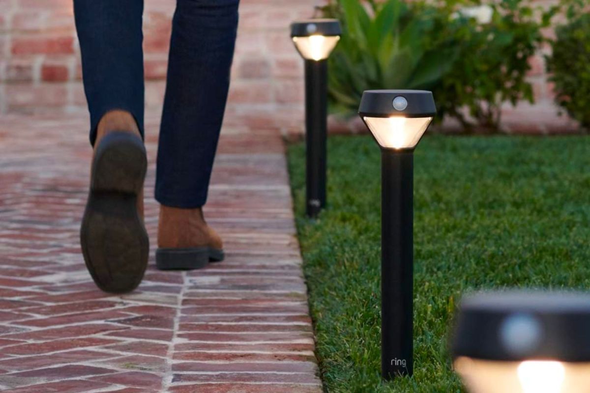 A man walking on a brick walkway next to the best smart outdoor lights option