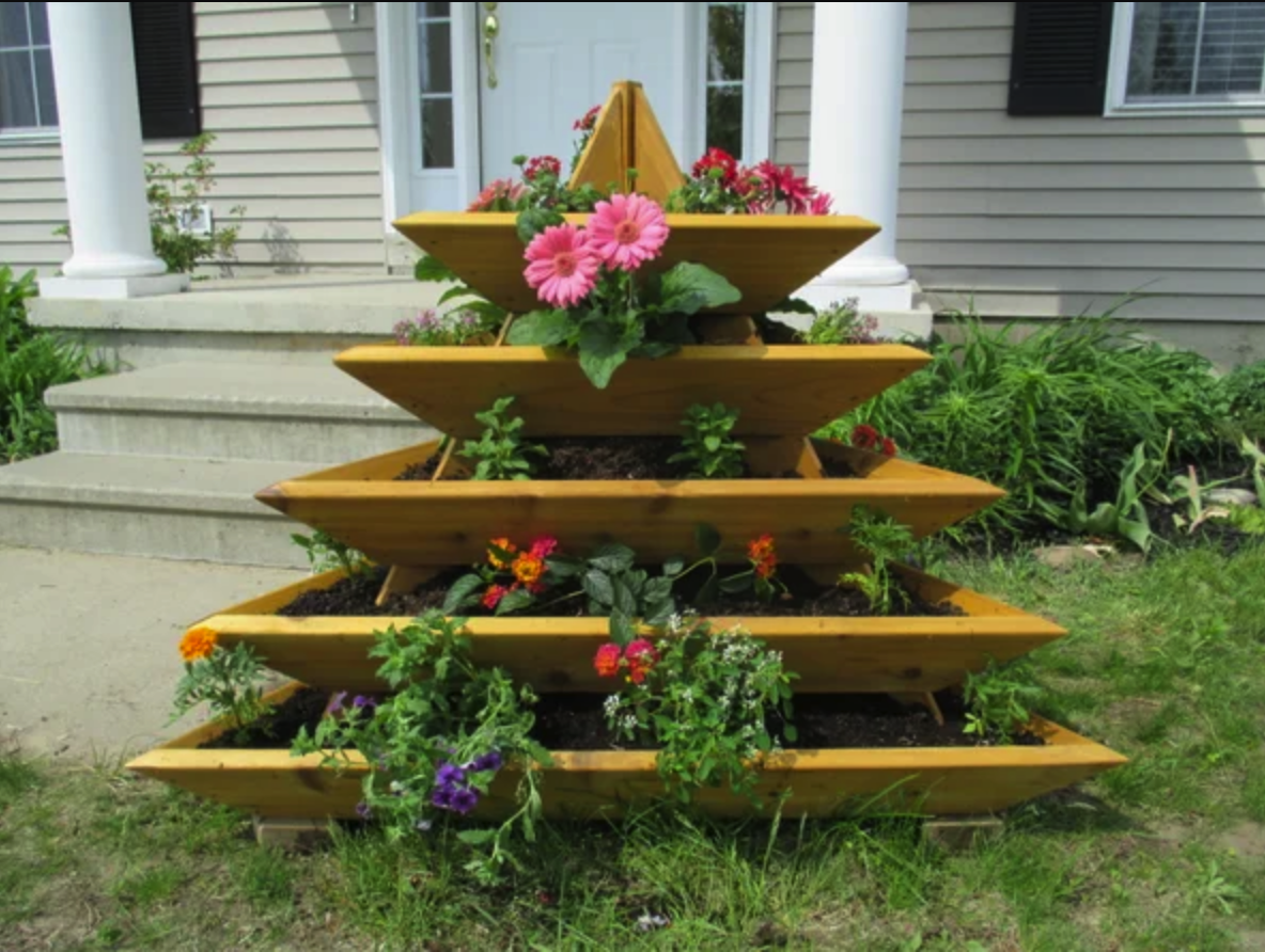 wood pyramid-shaped tiered garden mount with potted plants in front yard