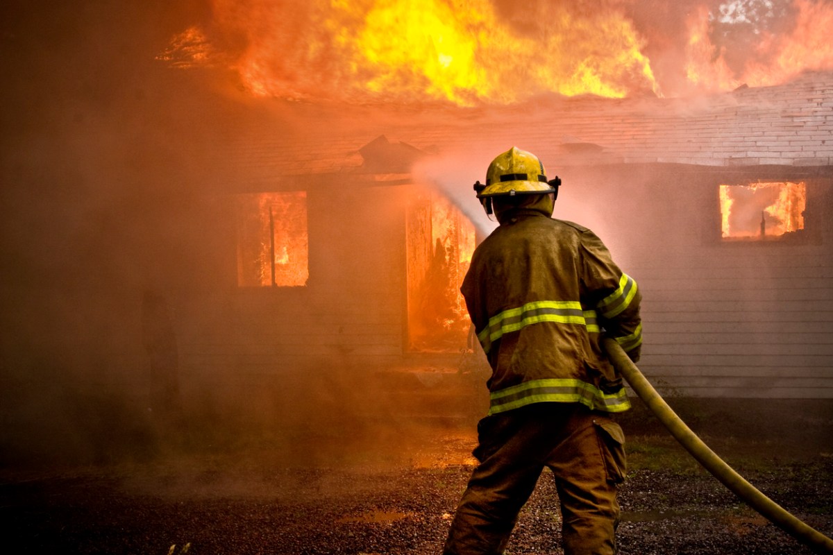 Firefighter spraying water on a big house fire