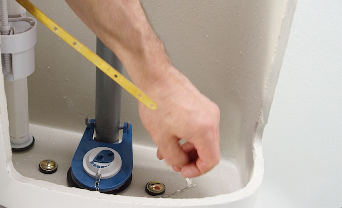 Person's hand installing new toilet flapper