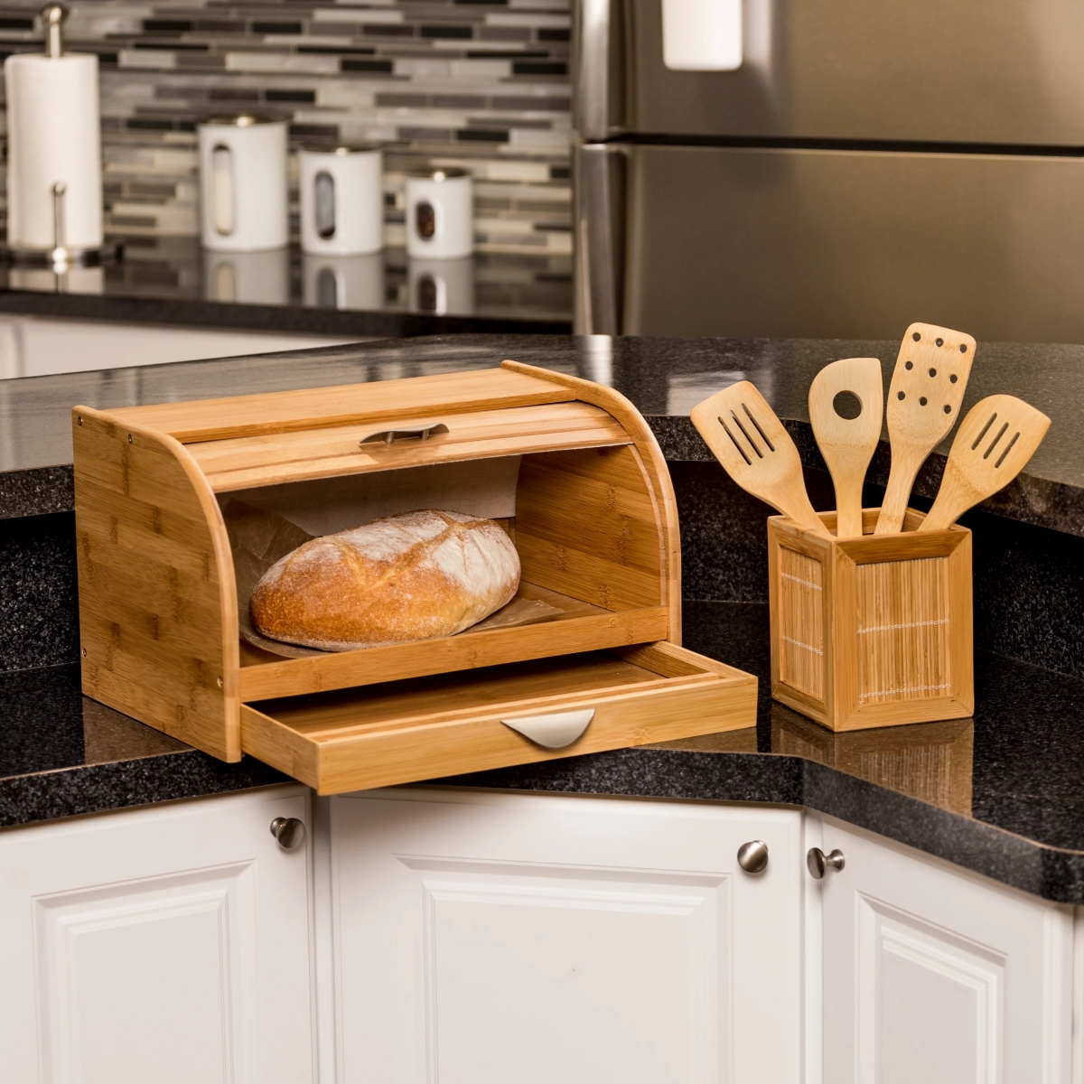 Wooden bread box on black kitchen counter with loaf of bread inside