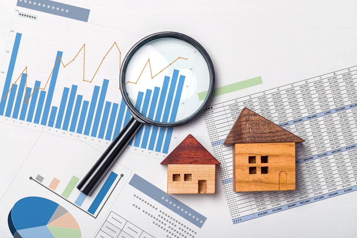 Magnifying glass on investment graphs with wooden mini houses
