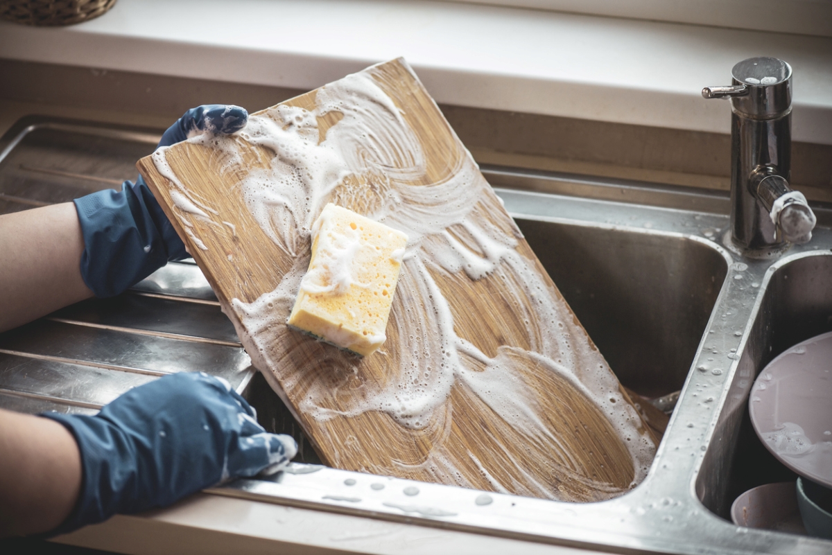 uses for hydrogen peroxide - gloved hands washing cutting board with sponge