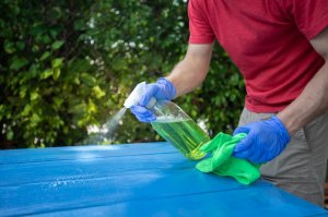uses for hydrogen peroxide - man spraying cleaning solution on blue table
