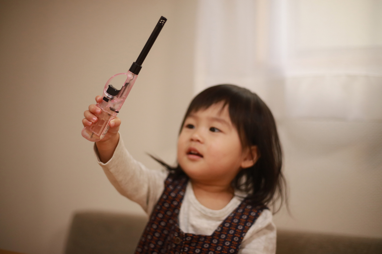 young girl with lighter raised over her head playing with it.