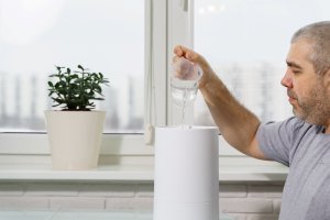 uses for hydrogen peroxide - man pouring water solution into humidifier