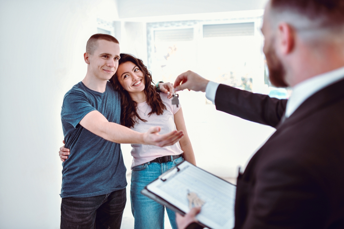 Young couple accepting house keys from agent