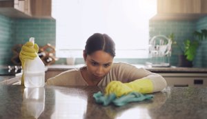 uses for hydrogen peroxide - woman looking closely while cleaning granite