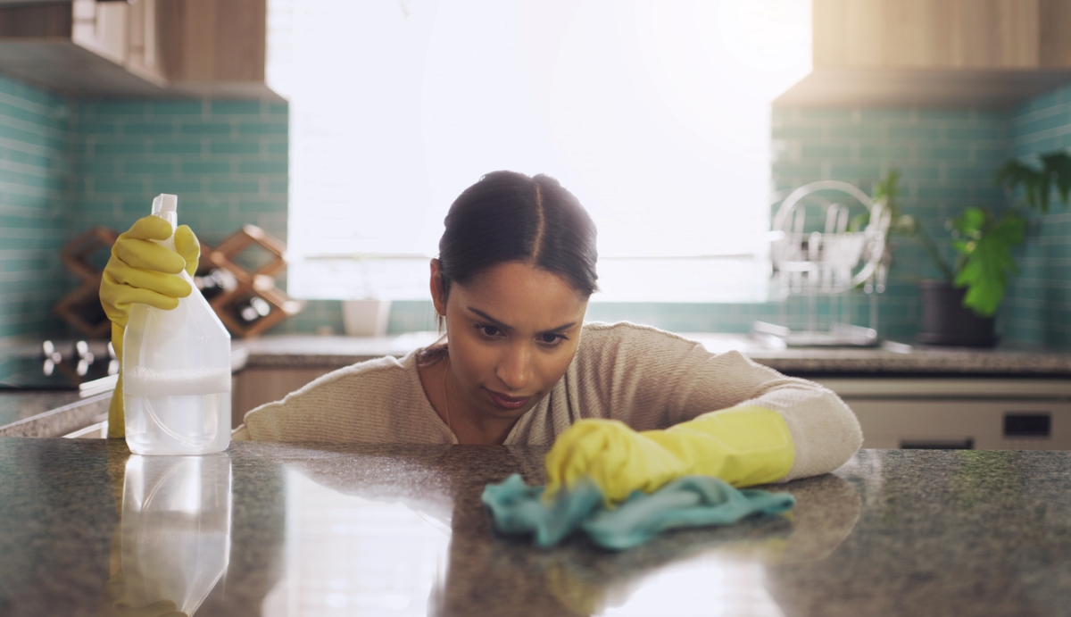 uses for hydrogen peroxide - woman looking closely while cleaning granite