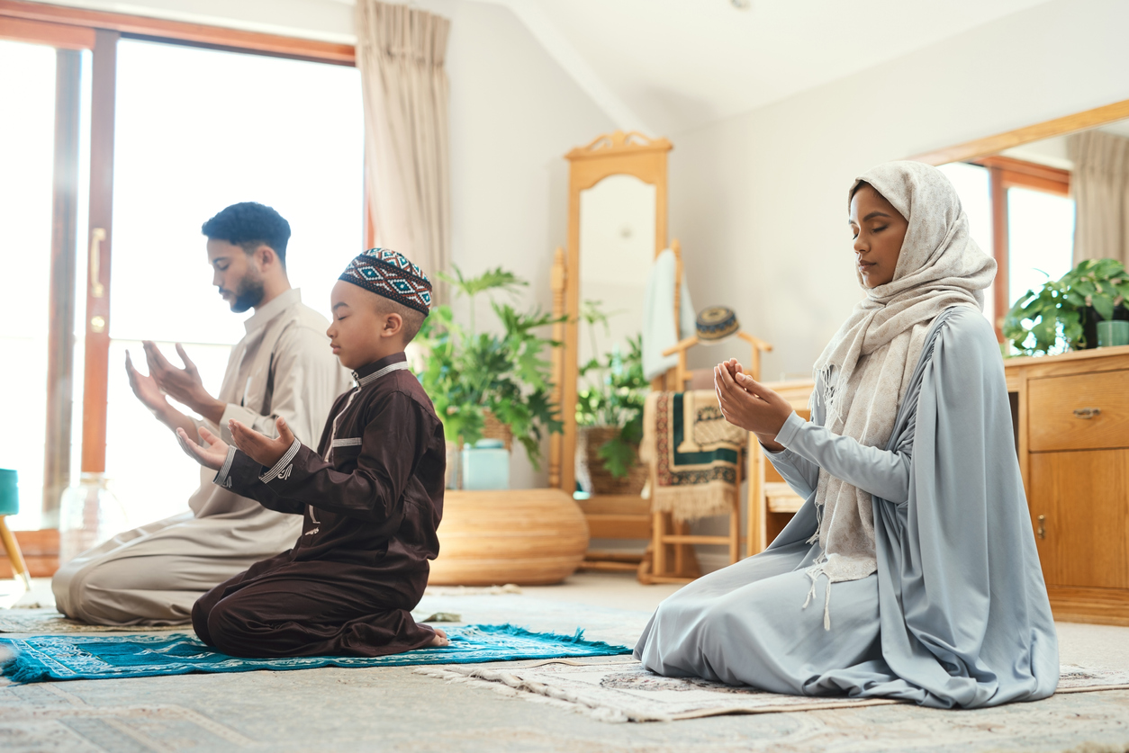 Shot of a young muslim couple and their son praying in the lounge at home