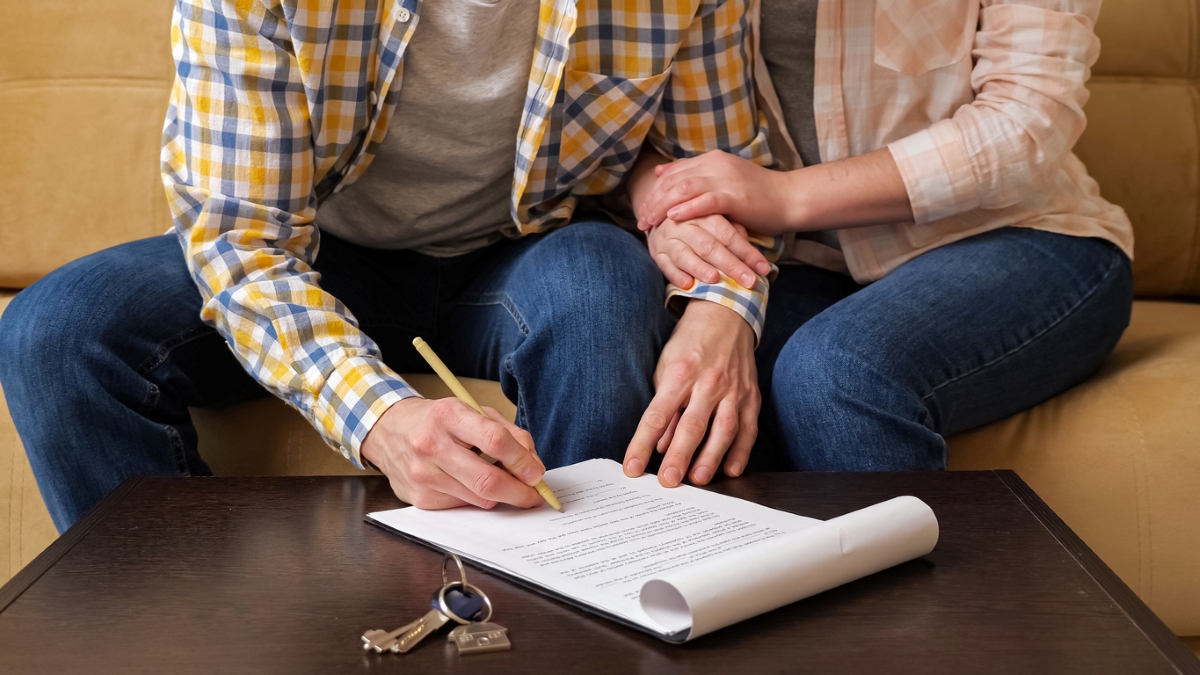 Couple signing lease with keys on table