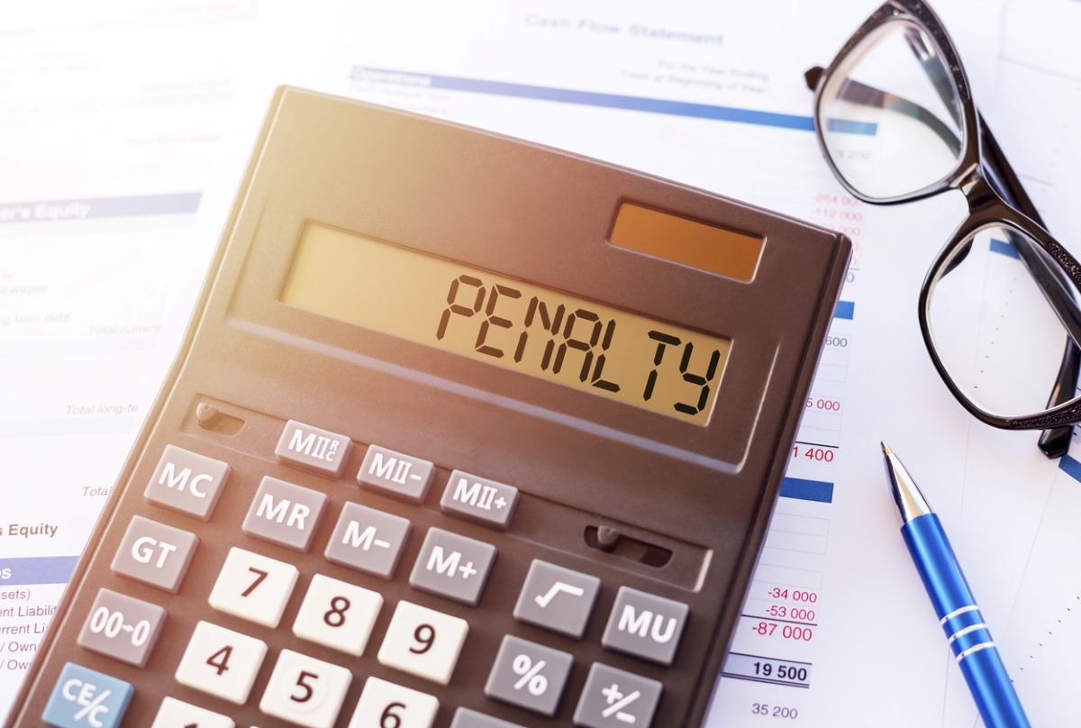 Word penalty written on calculator on financial documents