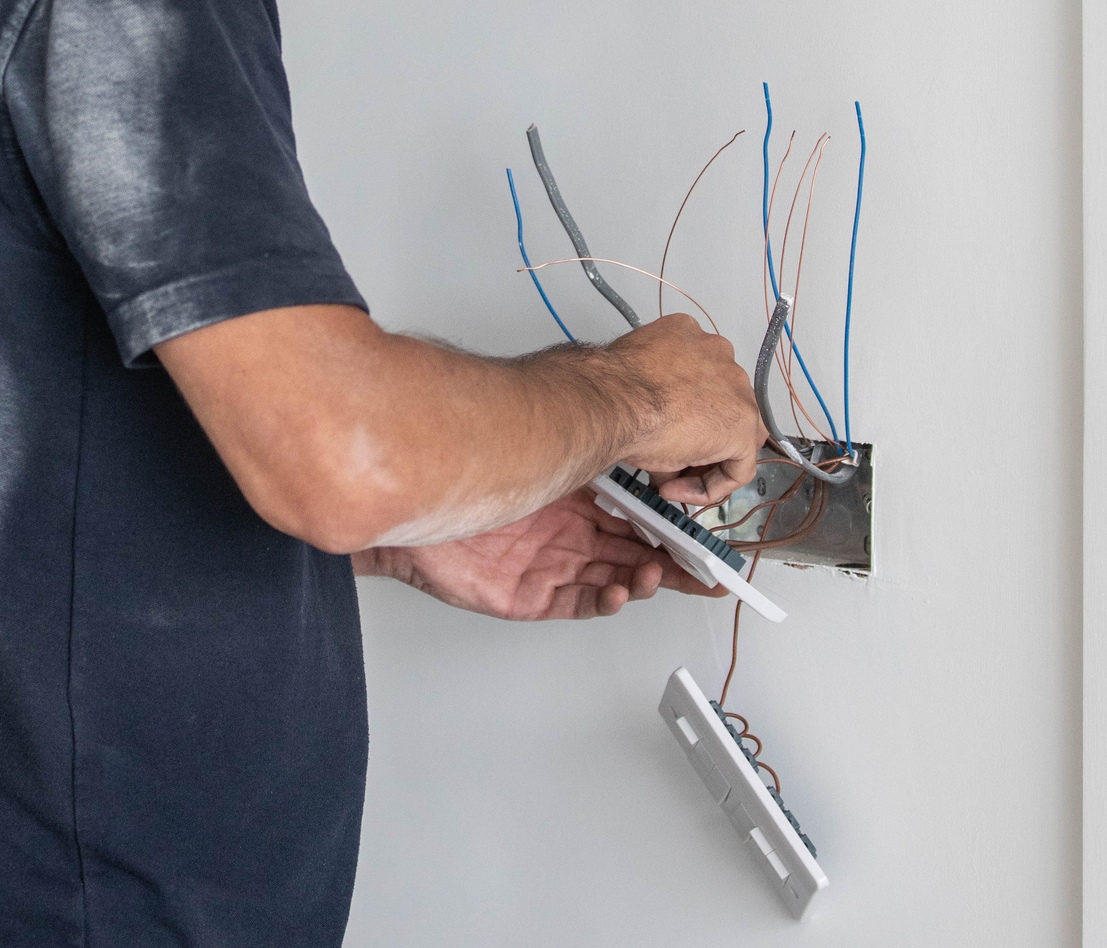 Electrician tradesman carrying out the final wiring of a residential property - connecting light switches
