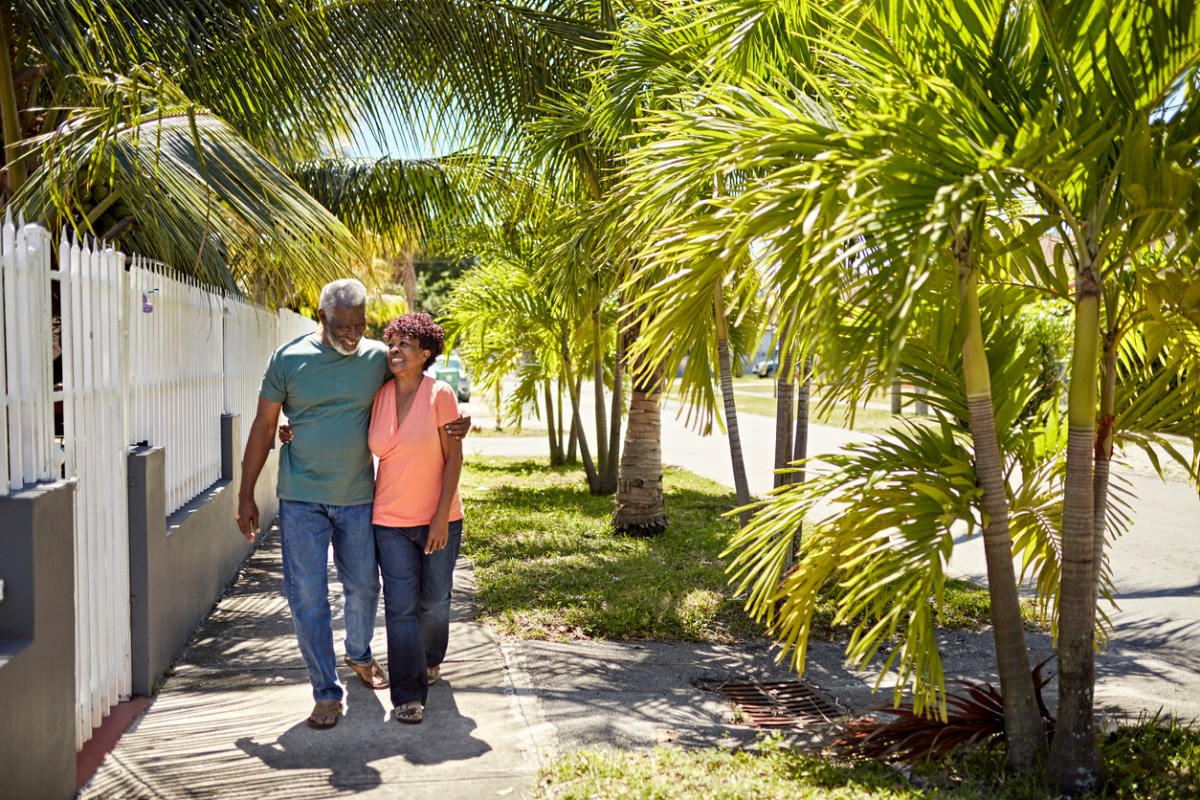 happy senior couple walking down residential street lined with palm trees