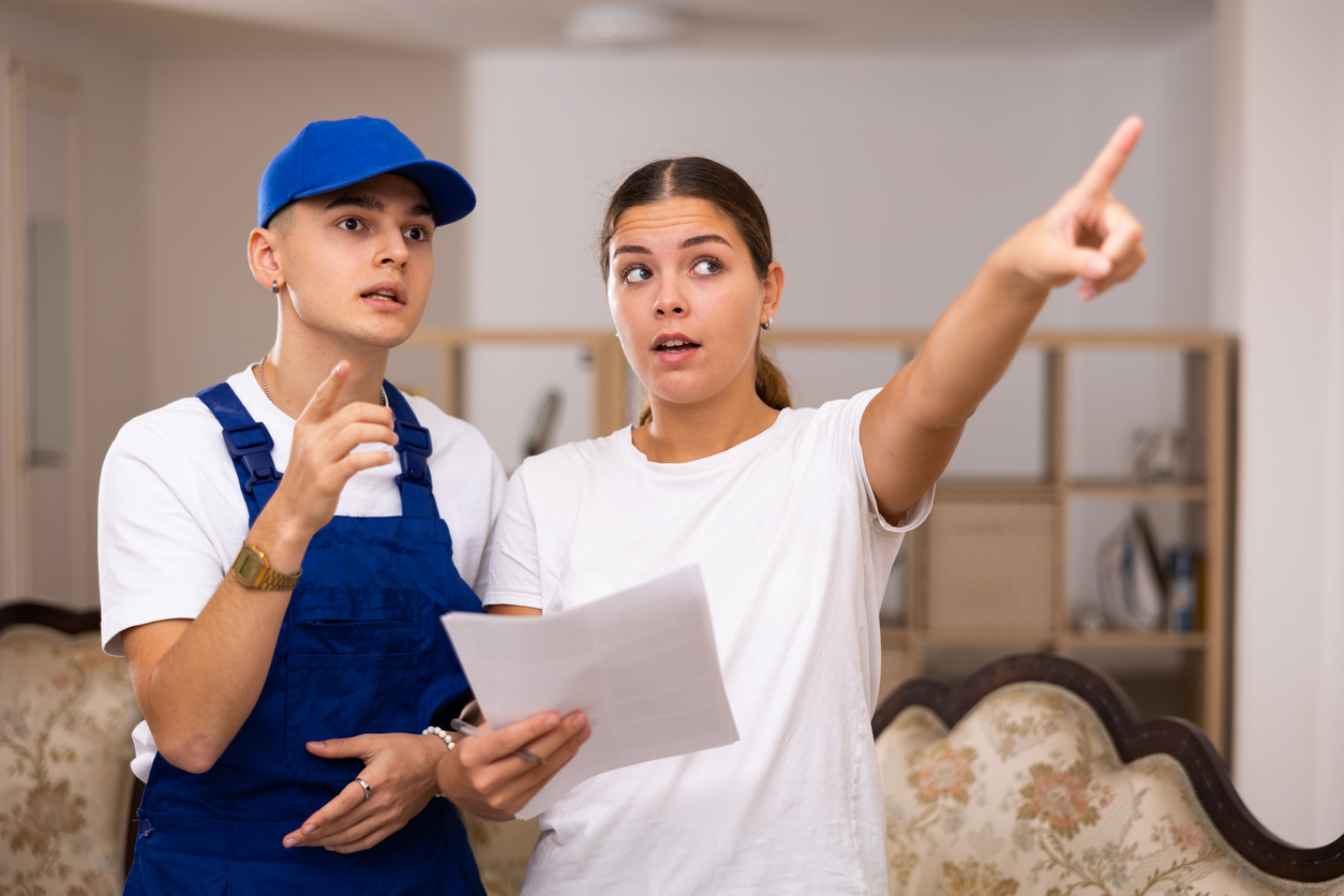 Landlady of an apartment explains to a young worker the plan of repair work