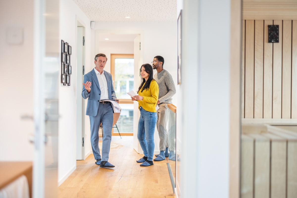 Male real estate agent showing young couple inside home