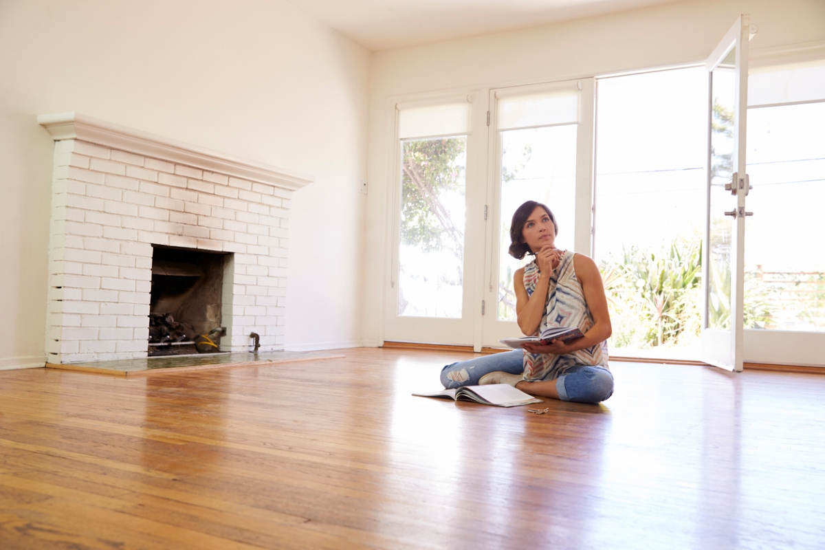 Woman sitting in empty living room thinking