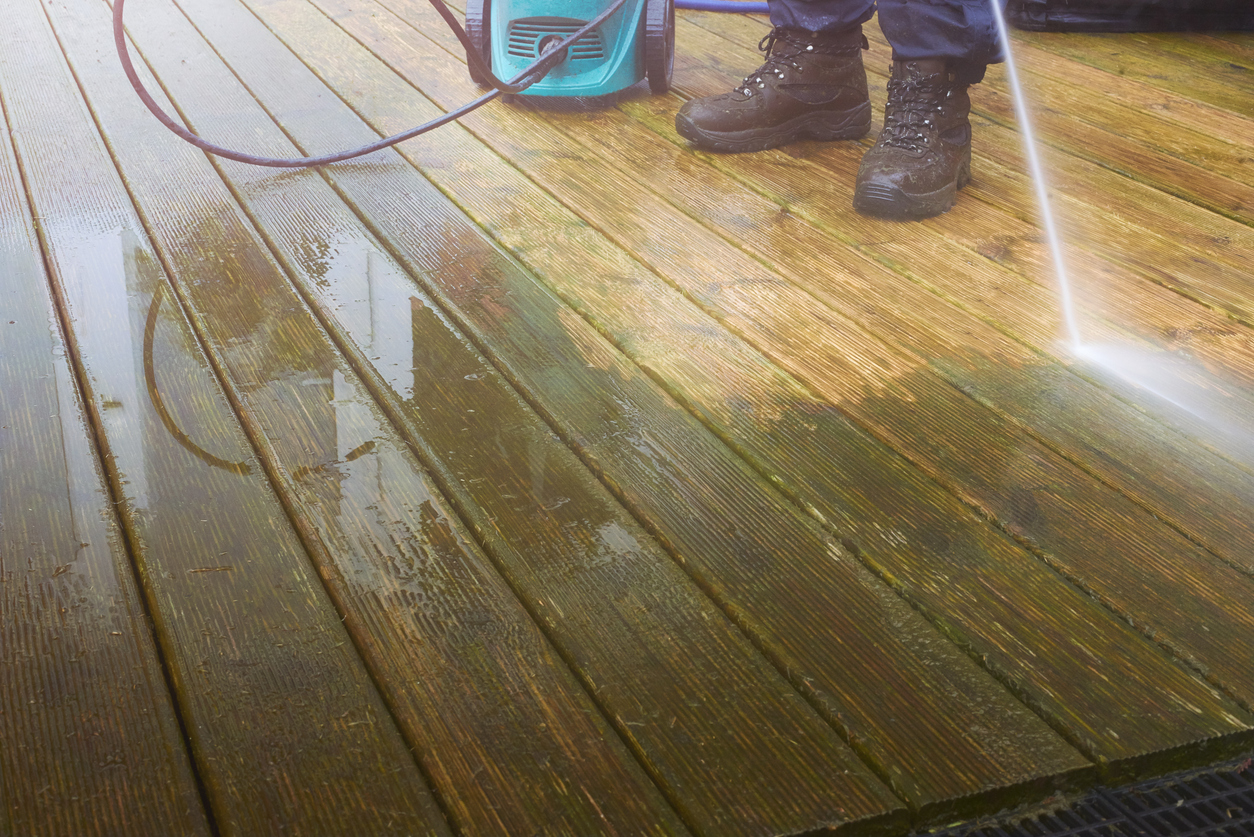 close up of someone power washing a stained deck