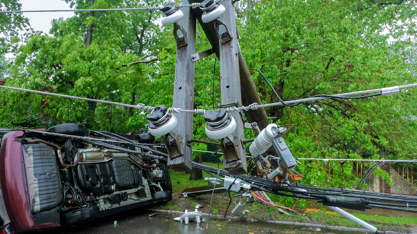 Damaged, overturned car hits a fallen utility pole.