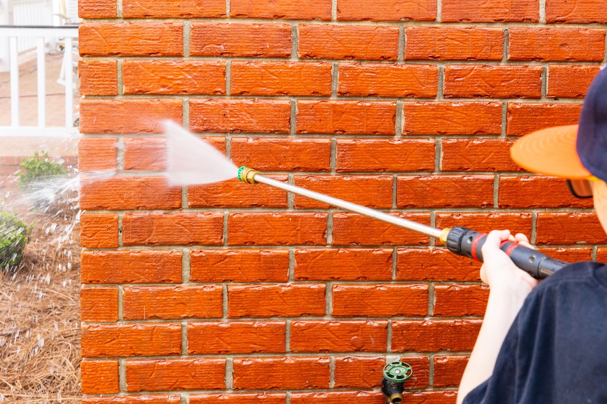 Brick wall being cleaned with water from pressure washer