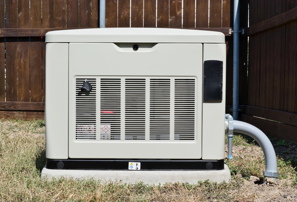 Home standby generator outside of wood house.