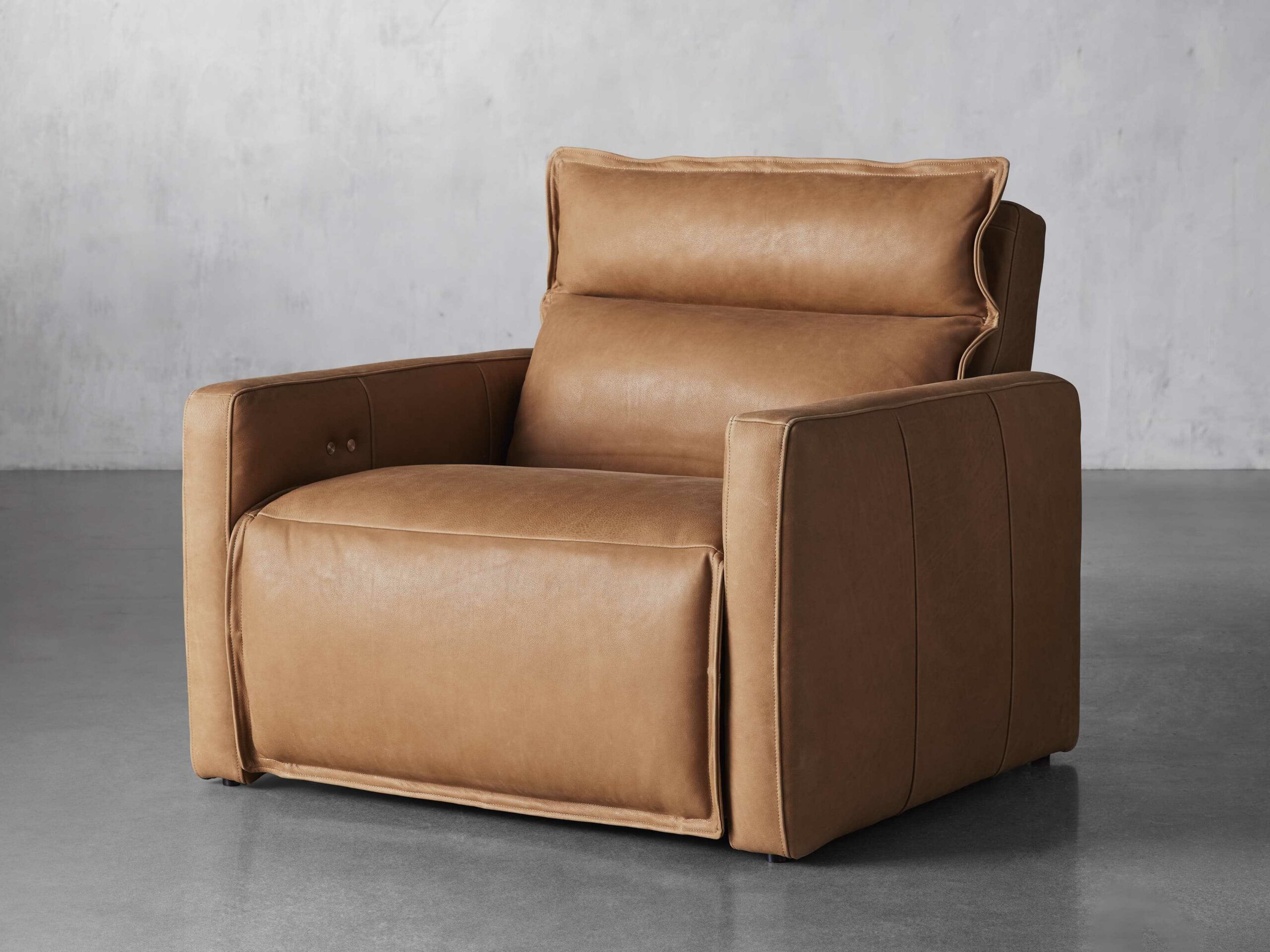 A camel brown leather Arhaus club chair recliner in a grey room