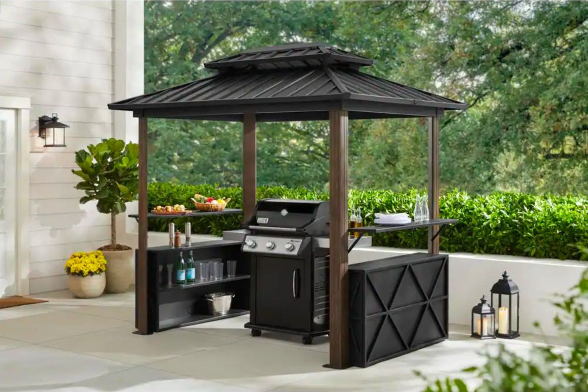 The best grill gazebos option on a cement patio covering a grill and stocked with grilling supplies