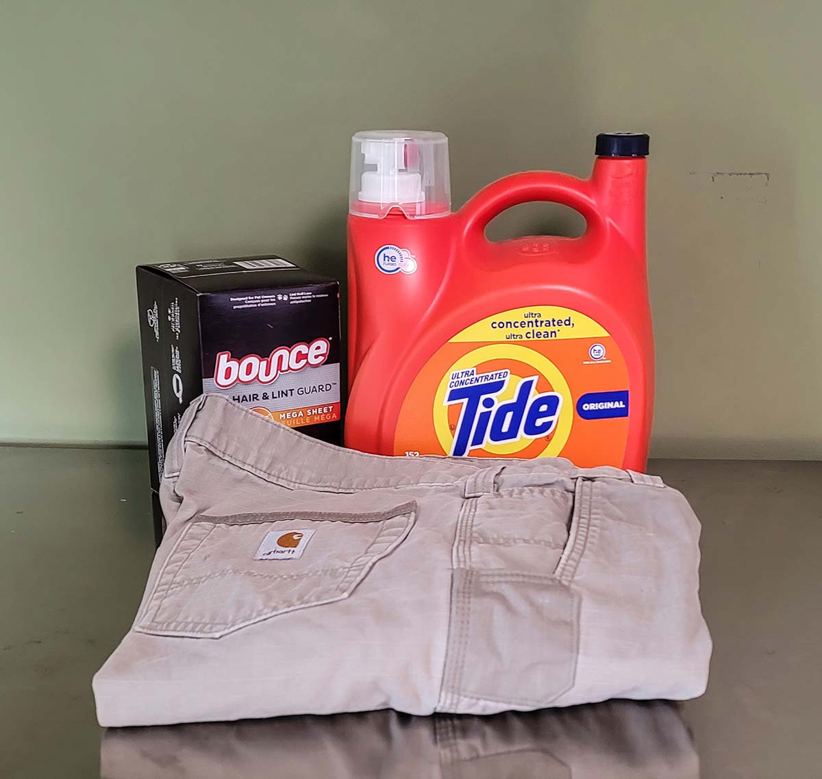 Pair of Carhartt Cargo Pants folded in front of laundry detergent and dryer sheets