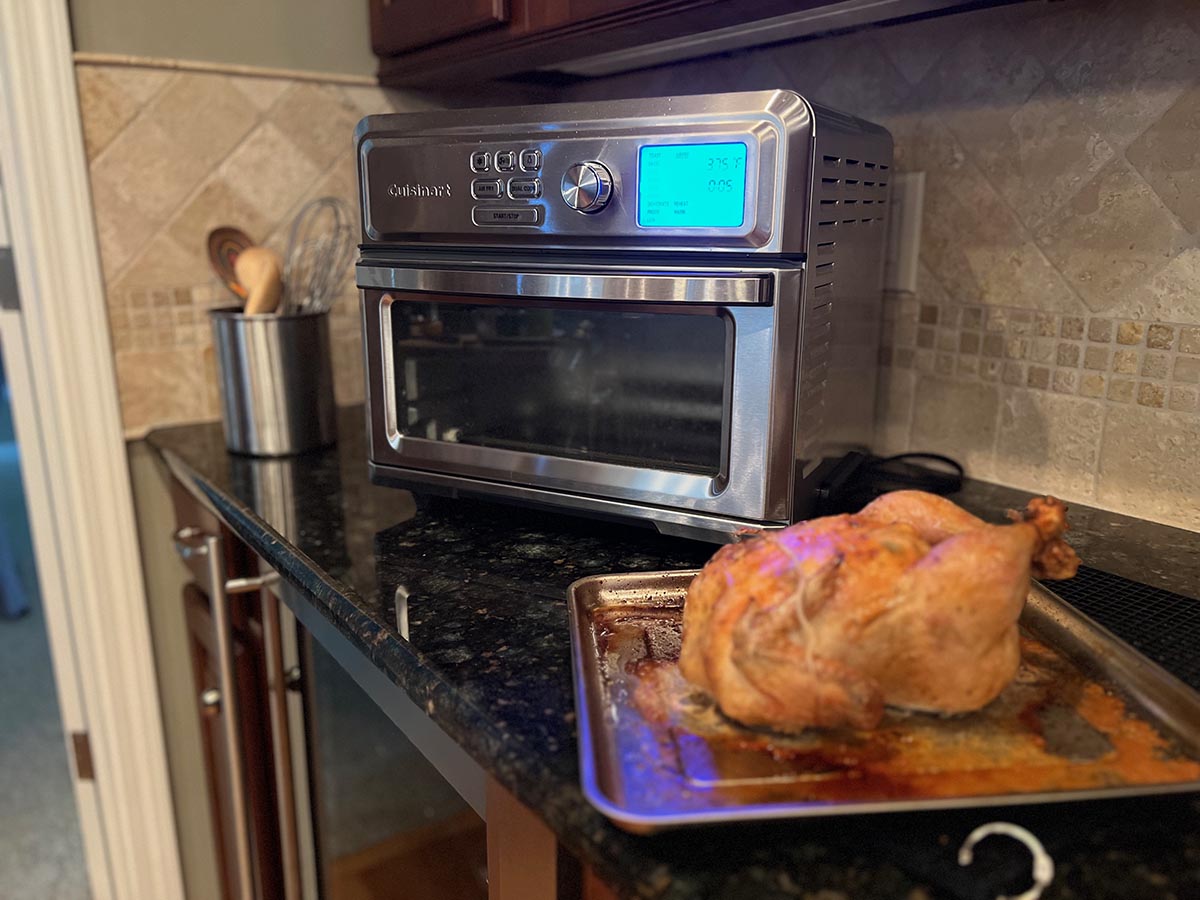 Roast chicken sitting in front of Cuisinart air fryer on counter