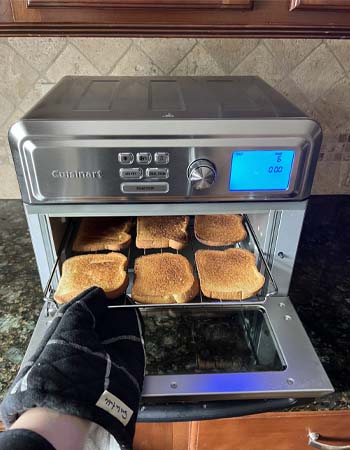 Person pulling toast out of Cuisinart air fryer toaster oven