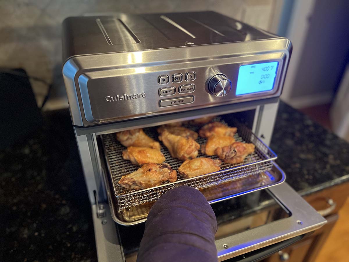 Person pulling chicken wings out of Cuisinart air fryer toaster oven