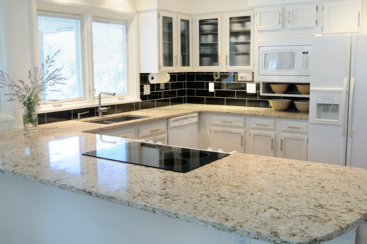 Long, seamless granite kitchen countertop enclosing bright kitchen on three sides