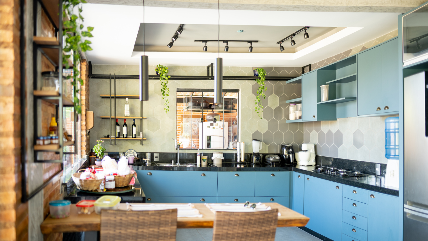 Colorful kitchen with bright blue cabinets, mint-and-gray hexagon tile backsplash, and natural accents